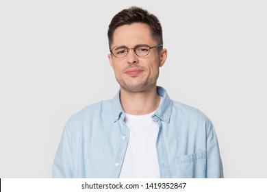 Head shot portrait dissatisfied man in eyeglasses frowning eyebrows having dissatisfied grumpy face expression posing over grey white studio background negative emotions irritated person concept image