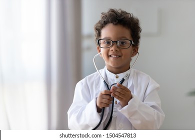 Head shot portrait funny African American little boy playing pediatrician doctor, preschool child wearing glasses, white uniform and stethoscope looking at camera, children healthcare insurance - Powered by Shutterstock