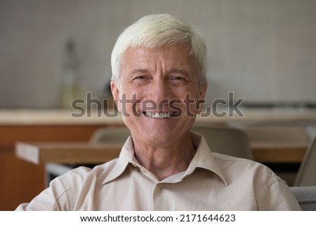 Head shot portrait handsome optimistic senior man sit indoor looking posing on camera, having wide toothy smile advertise professional dental clinic services for elders. Carefree retirement concept