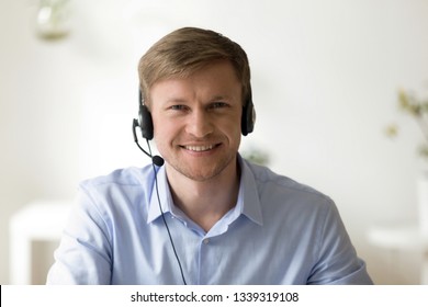 Head Shot Portrait Of Handsome Smiling Man Wearing Headset At Office Looking At Camera. Call Center Introduction. Happy Employee At Workplace. People At Work. Private Entrepreneur. Video Interview