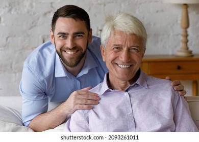 Head shot portrait handsome young man cuddling happy 60s old mature retired hoary father, posing at home. Loving friendly two male generations family looking at camera, trustful relations concept. - Powered by Shutterstock