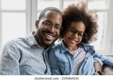 Head Shot Portrait Happy African American Father And Adorable Daughter Wearing Glasses Hugging, Looking At Camera, Loving Dad And Little Girl Child Bonding, Embracing, Posing For Photo Together