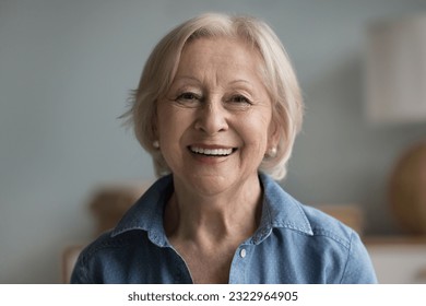 Head shot portrait happy beautiful retired woman. Mature female advertises professional services of dental clinic smile look at camera. Carefree life on retirement, medical insurance cover for seniors