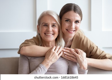 Head Shot Portrait Happy Loving Adult Daughter Hugging Older Mother, Smiling Young Woman And Mature Mum Or Grandmother Looking At Camera, Holding Hands, Family Photo, Two Generations Bonding