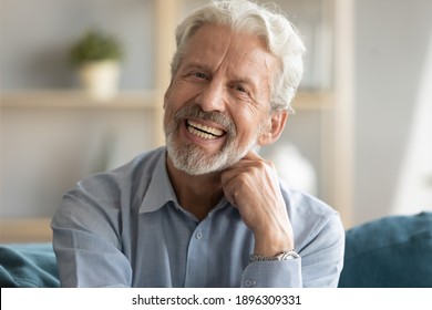 Head shot portrait of happy middle aged older retired man laughing at funny joke. Emotional smiling elderly grandfather looking at camera, enjoying video call or distant communicating with friends.