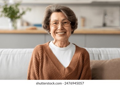 Head shot portrait of happy older European woman wearing eye glasses, looking at camera with toothy smile, posing at home - Powered by Shutterstock