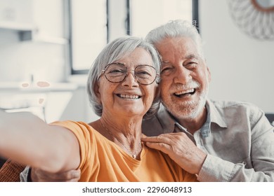 Head shot portrait happy senior couple taking selfie, having fun with phone cam, smiling aged wife and husband hugging, looking at camera, posing for photo, aged man vlogger recording video - Powered by Shutterstock