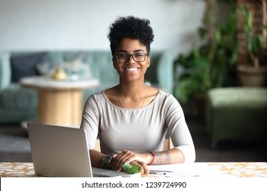 Head Shot Portrait Of Happy Smiling African American Woman Sitting At Table In Cafe, Looking At Camera, Excited Female Posing, Working At Computer, Doing Homework, Preparing Report In Coffee House