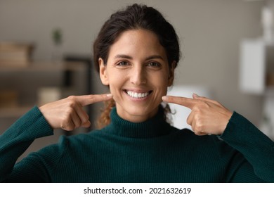 Head shot portrait happy woman pointing fingers at healthy toothy smile, straight white teeth, excited satisfied client recommending dental whitening service or toothpaste, oral hygiene concept