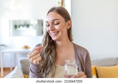 Head shot portrait happy woman holds pill glass of water, takes daily medicine vitamin D, omega 3 supplements, skin hair nail strengthen and beauty, medication for health care concept