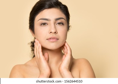 Head Shot Portrait Indian Woman Touching Perfect Smooth Face Skin, Looking At Camera, Young Female With Bare Shoulders, Natural Beauty Concept, Close Up Isolated On Brown Studio Background