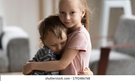 Head shot portrait of little kid girl cuddling smaller brother at home, showing love and care. Compassionate sister comforting soothing upset stressed boy in living room, siblings relations concept. - Powered by Shutterstock