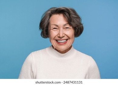 Head shot portrait overjoyed aged mature woman female pensioner laughing feels happy pose isolated on blue studio background, advertise clinic procedure dental care prosthesis for seniors - Powered by Shutterstock