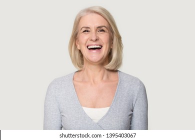 Head shot portrait overjoyed blond middle aged female smiling look at camera laughing feels happy pose isolated on grey studio background, advertise clinic procedure dental care prosthesis for seniors