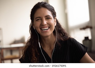 Head shot portrait overjoyed woman wearing earphones laughing at camera, excited happy young female making video call, enjoying pleasant conversation, blogger recording vlog, having fun with webcam