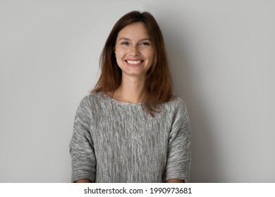 Head shot portrait of positive beautiful woman posing on grey studio background isolated, happy young female with healthy toothy smile and perfect smooth skin looking at camera, natural beauty - Shutterstock ID 1990973681