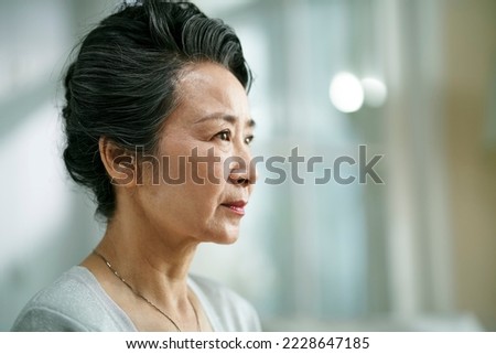 head shot portrait of a sad asian old woman, side view