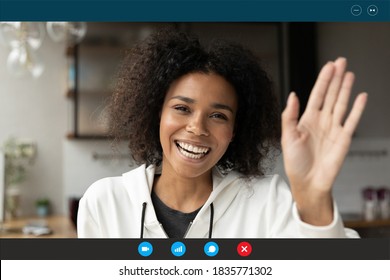 Head shot portrait screen view smiling African American woman greeting, waving hand, making video call to friends or relatives, looking at camera, using webcam and social media apps, engaged webinar