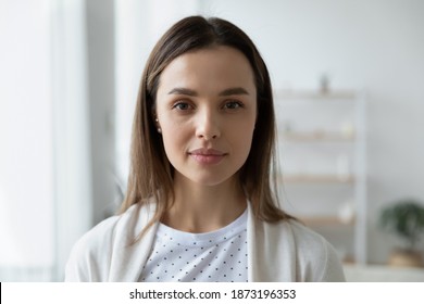 Head shot portrait serious beautiful young woman with perfect smooth skin looking at camera, standing at home, profile picture, focused attractive girl shooting video, recording vlog, job interview