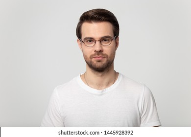 Head Shot Portrait Of Serious Confident Millennial Man Wearing Glasses White T-shirt Posing On Grey Studio Background, Guy Advertise Lens Eyewear Store Sale, Eyesight Laser Vision Correction Concept