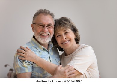 Head Shot Portrait Of Sincere Happy Older Generation Family Couple Cuddling At Home. Smiling Middle Aged Mature Retired Woman And Man Homeowners Posing In Own Apartment, Showing Sweet Tender Feelings.