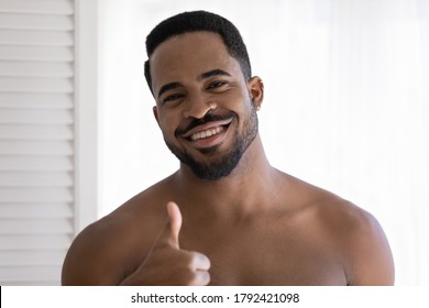 Head Shot Portrait Smiling African American Young Man With Naked Shoulders Showing Thumb Up Gesture Close Up, Enjoying Skincare Procedure, Cosmetics Product Quality, Morning Routine