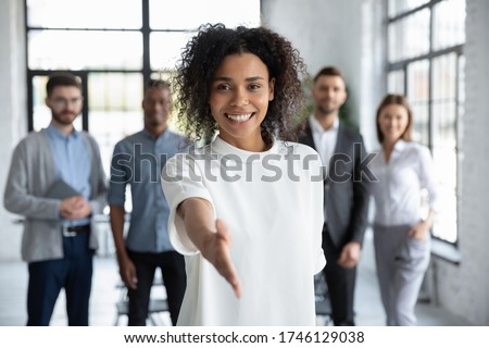 Head shot portrait smiling African American businesswoman offering handshake, standing with extended hand in modern office, friendly hr manager or team leader greeting or welcoming new worker
