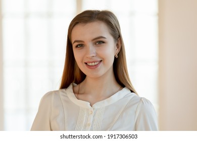 Head shot portrait of smiling attractive young woman. Happy millennial patient satisfied with provided medical services in clinic. Beautiful joyful businesswoman standing in office, looking at camera.
