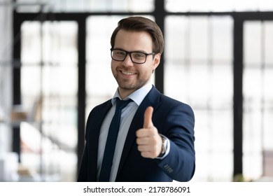 Head shot portrait smiling businessman wearing suit and glasses showing thumb up and looking at camera, successful employee or hr manager recommending company service, giving recommendation