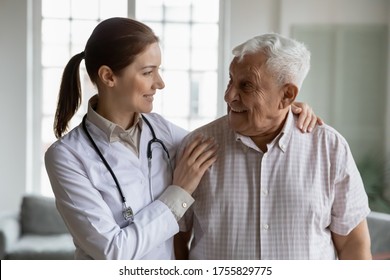 Head Shot Portrait Smiling Caring Female Doctor Hugging Older Man, Standing Together, Young Woman Caregiver Wearing White Coat And Stethoscope Supporting Mature Senior Patient, Healthcare Concept