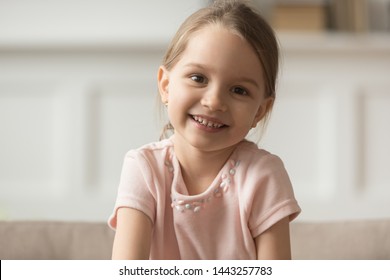 Head Shot Portrait Of Smiling Little Girl Looking At Camera, Preschool Child Playing With Camera, Recording Vlog Or Making Video Call, Communicating Online, Using Webcam, Sitting On Couch At Home