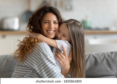 Head shot portrait smiling loving mother hugging adorable little daughter, looking at camera, caring happy mum and cute preschool girl enjoying tender moment, sitting on cozy couch at home - Shutterstock ID 1835861803