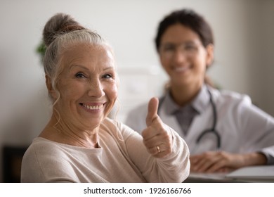 Head shot portrait smiling mature female patient showing thumb up, female therapist and senior man sitting in doctor office, old client satisfied by health insurance or healthcare service concept