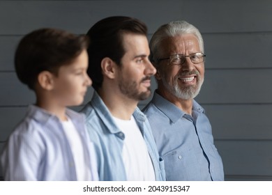 Head Shot Portrait Of Smiling Senior Man In Glasses With Son And Little Grandson Standing On Grey Wooden Wall Background In Row, Three Generations Of Men, Multigenerational Family Unity Concept