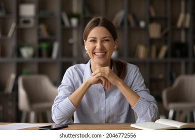 Head shot portrait of smiling woman in earphones looking at camera, successful businesswoman involved in online conference or negotiations, making video call, mentor coach leading internet lesson