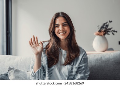 Head shot portrait smiling woman making video call to friends or relatives, using webcam, sitting on couch at home, happy young female blogger recording vlog, looking at camera, chatting online - Powered by Shutterstock