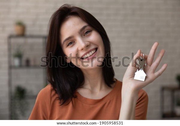 Head shot portrait smiling woman tenant showing\
keys to new apartment, looking at camera, happy female customer\
excited by purchasing new house, moving to first dwelling, mortgage\
or rent concept