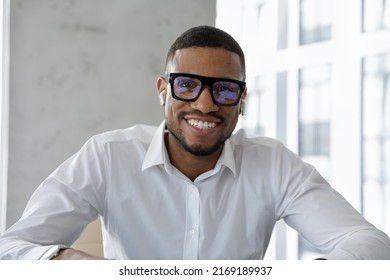 Head Shot Portrait Successful African Businessman Make Videocall To Client Smile Looks At Cam Wear Wireless Earphones Listen Counsellor, Take Part In Business Virtual Meeting By Video Conference Apps