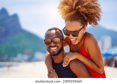 head shot portrait young black brazilian couple in piggyback position having fun in Ipanema beach Brazil	 - Powered by Shutterstock