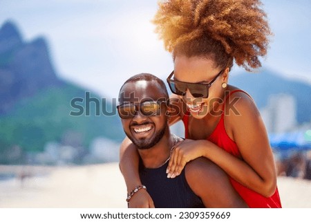 head shot portrait young black brazilian couple in piggyback position having fun in Ipanema beach Brazil	