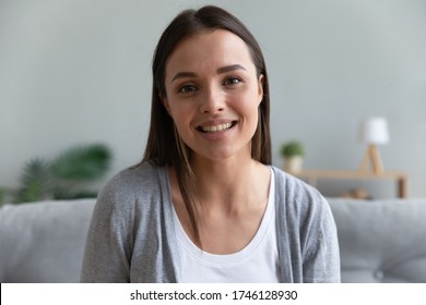 Head shot portrait young woman sit on couch looks at camera has conversation via distant chat using computer webcam, informal talk with friend, e-dating, girl records vlog, pass job interview concept - Shutterstock ID 1746128930