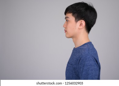 Head Shot Profile View Of Young Asian Man Against White Background