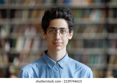Head shot schoolboy guy posing in campus library on bookshelves background. 17s pupil in eyeglasses look at cam. Excellent student portrait, skill and knowledge, education, generation Z person concept - Shutterstock ID 2139744613