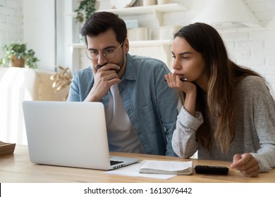 Head Shot Serious Married Couple Looking At Computer Screen, Using Banking Application, Sitting Together At Table. Thoughtful Family Spouse Confused By High Bills, Insurance Payment Or Rent Charge.