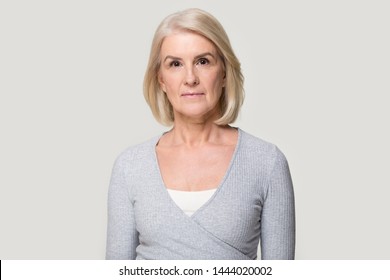 Head shot of serious old aged woman looking at camera. Elderly female portrait, person in years. Successful businesswoman, ceo, director, manager, banker, hr. Studio photo isolated on grey background