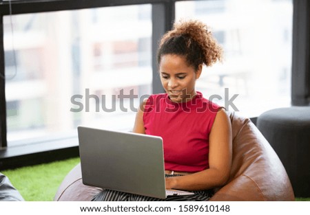 Head shot of smiling African american female using laptop in cafe