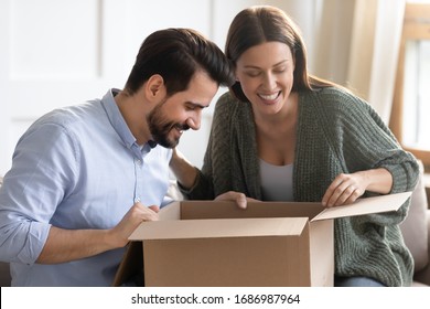 Head Shot Smiling Young Customers Open Carton Box At Home, Interested In Purchased Items. Happy Pleasant Family Couple Unboxing Purchase From Internet Store, Satisfied With Fast Delivery Shipping.