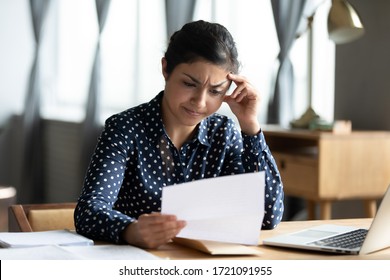 Head Shot Stressed Unhappy Millennial Indian Girl Looking Through Paper Document. Upset Hindu Woman Feeling Nervous About Bank Debt Notification, Worrying About Financial Problems, Dismissal Letter.