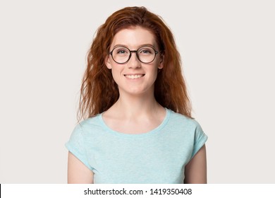 Head shot studio portrait caucasian smiling red-headed woman girl wearing blue t-shirt glasses looking at camera isolated on grey or white background, eyewear advertisement, optics store offer concept