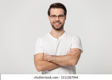 Head shot studio portrait happy millennial confident man in glasses standing with folded hands. Motivated smiling young male professional looking at camera posing isolated on grey white background. - Shutterstock ID 1511367044